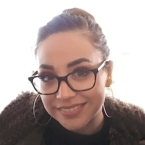Latina female with brown hair in a bun wearing glasses and smiling